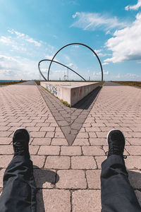 Low section of person relaxing against sky