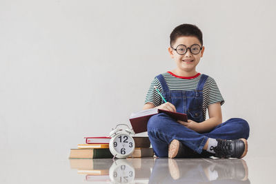 Portrait of boy sitting against wall