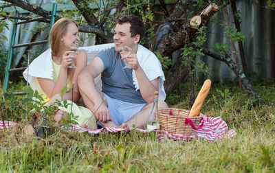 Smiling couple drinking white wine during picnic in garden