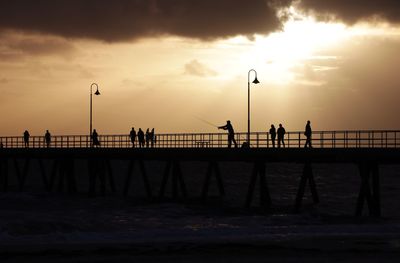 Silhouette people on pier against sky during sunset