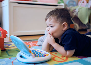 Curious little toddler playing with his toy computer