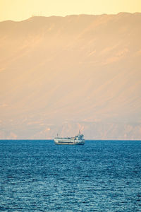 Sailboat sailing on sea against sky during sunset