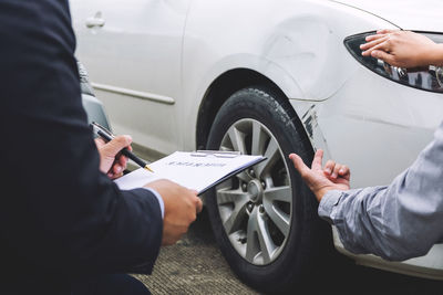 Cropped image of customer gesturing while insurance agent holding clipboard