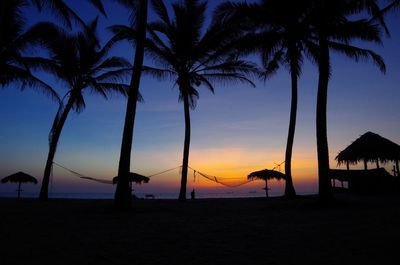 Silhouette palm trees on beach against sky during sunset