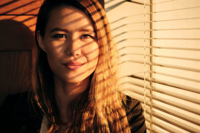 Portrait of smiling young woman standing by window