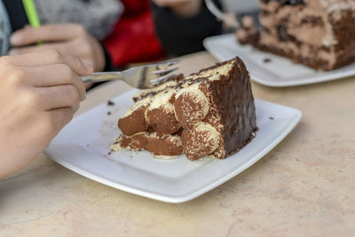 Close-up of hand holding dessert in plate on table