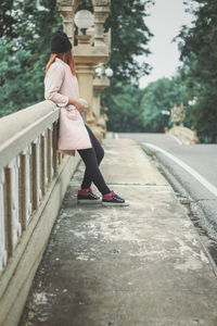 Woman standing by railing in city