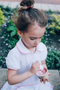 High angle view of cute girl holding ice cream while sitting outdoors