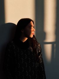 Young woman standing against wall at home