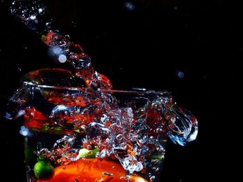 Close-up of glass over water against black background