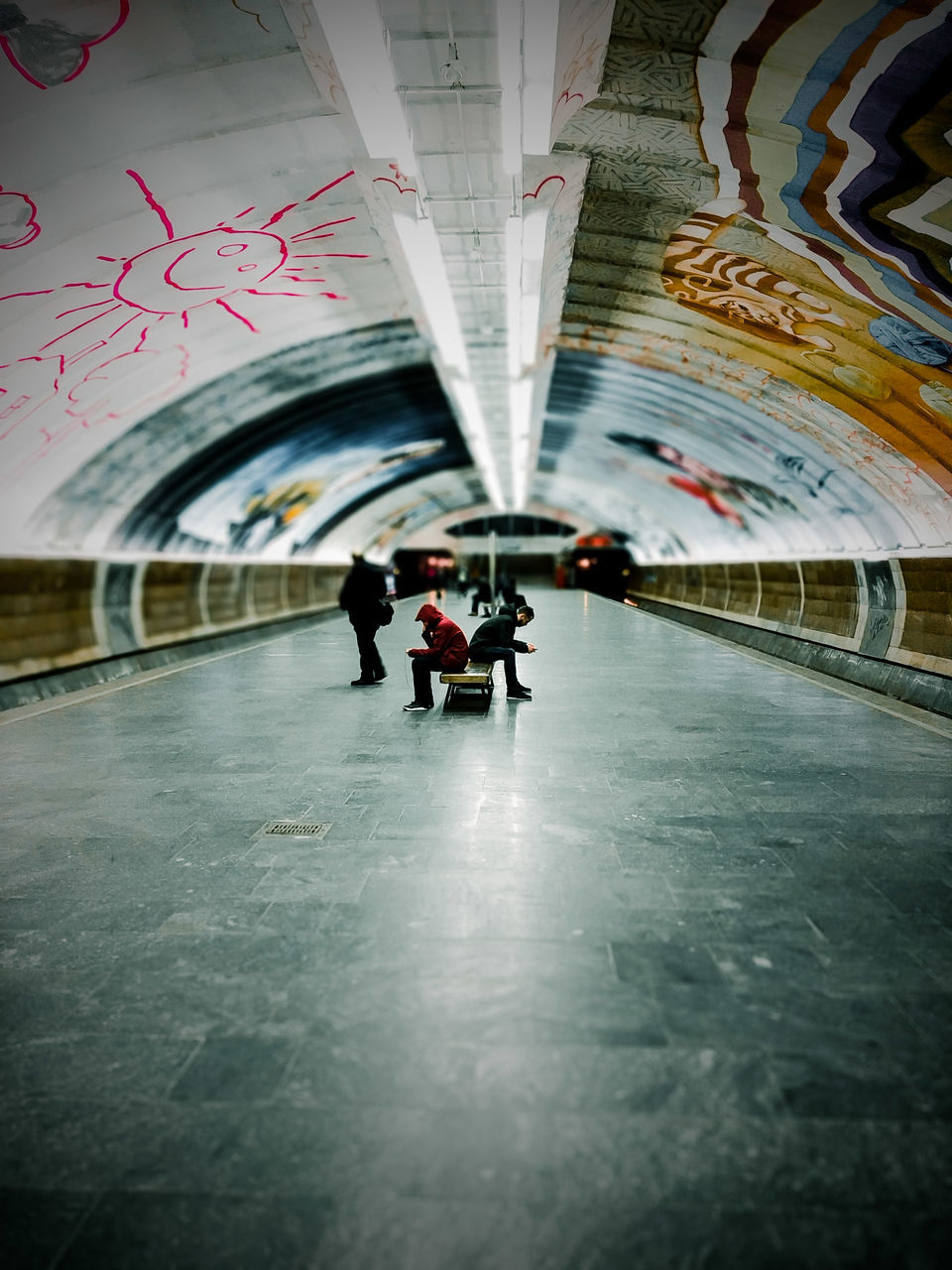 REAR VIEW OF PEOPLE WALKING IN ILLUMINATED SUBWAY