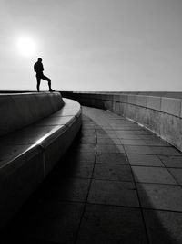 Silhouette man standing on railing against sky