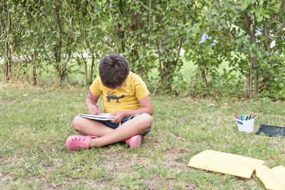 Young boy outdoors on the grass at backyard using his tablet computer. educating and playing.