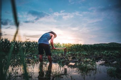 Man standing on field against sky during sunset