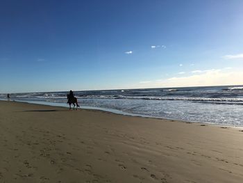 Woman walking on beach against sky