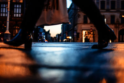 Low section of woman walking on street at night