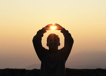 Silhouette man standing against orange sky during sunset