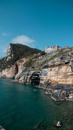 Rock formations by sea against blue sky