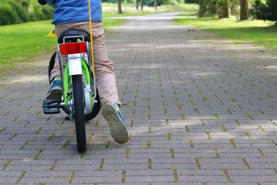 Rear view of man riding bicycle on footpath