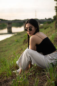 Side view of young woman sitting on field