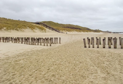 Wooden posts on beach against sky