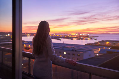 Rear view of woman looking at cityscape during sunset