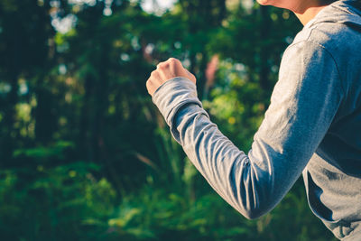 Midsection of woman running against trees