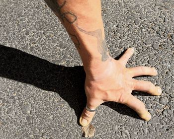 Cropped hand on road during sunny day