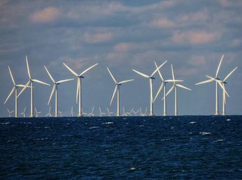 Wind turbines in sea against sky