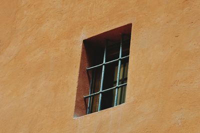 Low angle view of window on orange wall