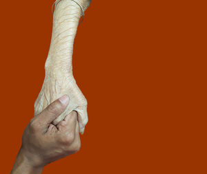 Close-up of hand against orange background