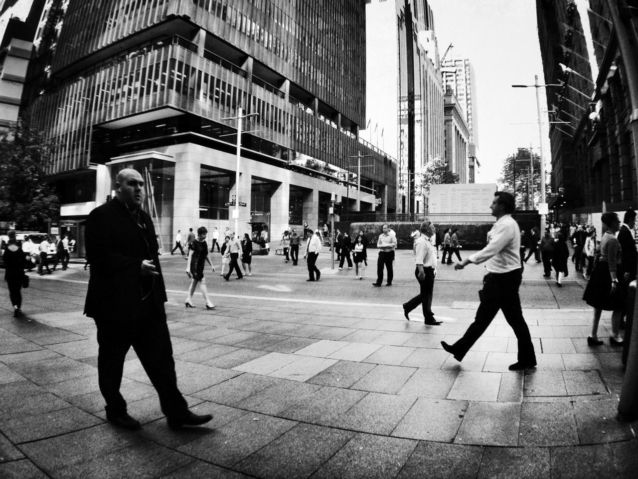 building exterior, architecture, city, built structure, person, large group of people, city life, walking, men, lifestyles, street, leisure activity, full length, city street, sidewalk, building, town square, outdoors, pedestrian