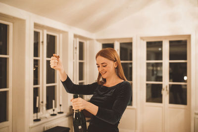 Full length of woman standing against window at home