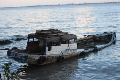 Abandoned boat in sea against sky