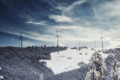 Wind turbines on field against sky