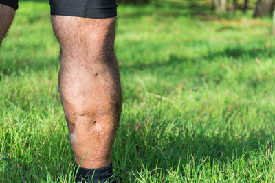 Low section of man wearing shoes on grass