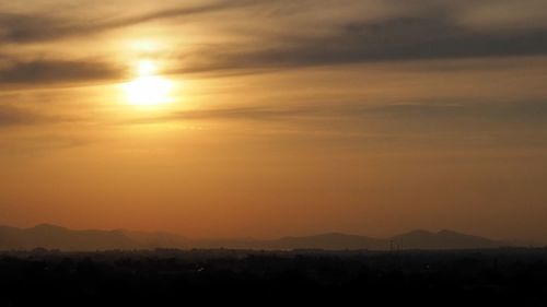 Scenic view of silhouette mountains against orange sky