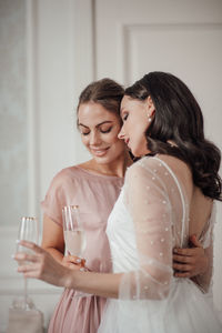 Bridesmaid and bride holding champagne flute