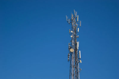 Low angle view of communications tower against blue sky