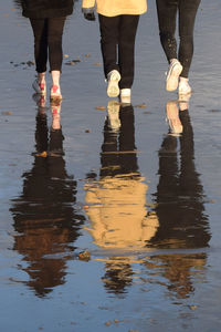 Low section of people standing on wet water