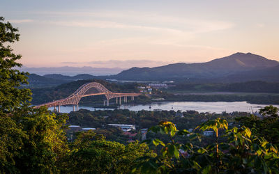 Scenic view of river by mountains against sky during sunset