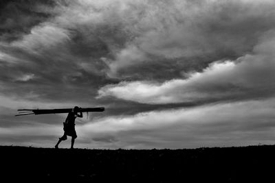 Silhouette man standing on field against sky at sunset