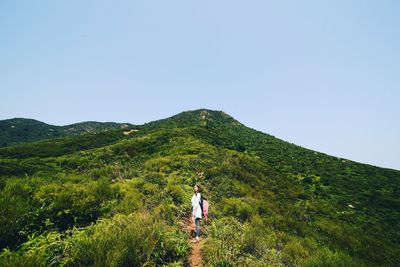 Woman hiking on green landscape against sky