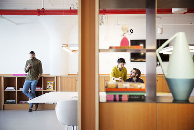 Businessman using mobile phone while colleagues working in office