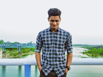 Portrait of young man standing against railing