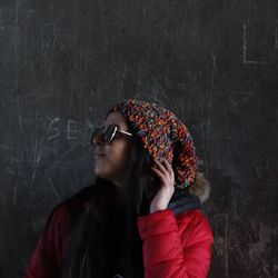 Woman wearing sunglasses while standing against blackboard