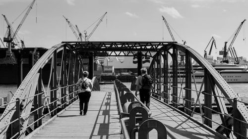 Rear view of people walking on bridge in city