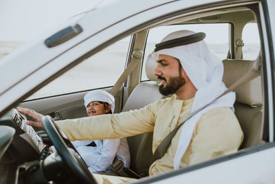 Father and son sitting in car at desert