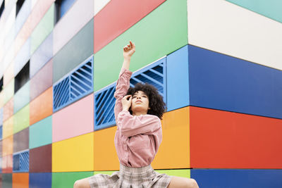 Full length of woman standing against multi colored wall