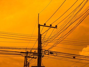 Low angle view of electricity pylon against sky during sunset